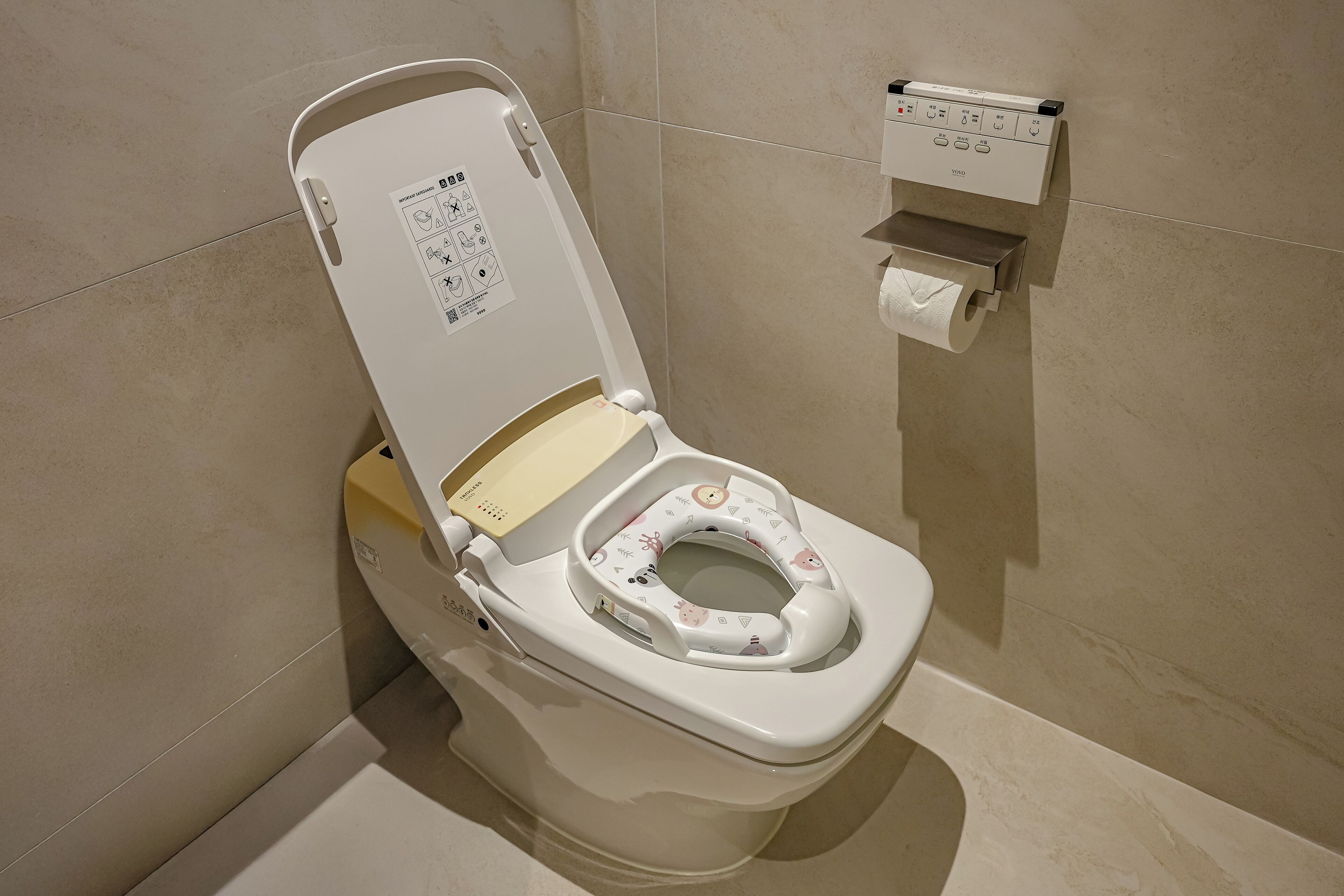 A modern toilet with a child seat, a toilet paper holder, and a control panel.