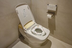 A modern toilet with a child seat, a toilet paper holder, and a control panel.