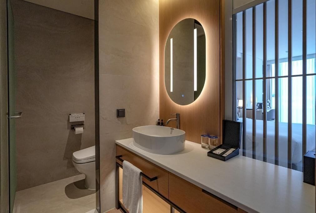 Un baño moderno con un espejo redondo, un lavabo blanco y un inodoro.