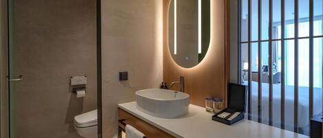 Un baño moderno con un espejo redondo, un lavabo blanco y un inodoro.