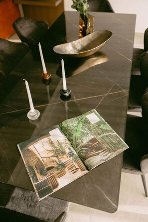 Una mesa de comedor con tres velas, un bol y un libro con una imagen de un paisaje.
