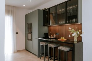 Cocina moderna con horno empotrado, taburetes de bar y una vitrina para vinos.