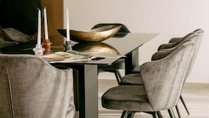 Un espace repas moderne avec une table sombre, des chaises à revêtement gris et un vase décoratif servant de centre de table.