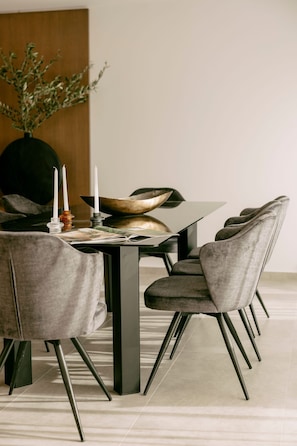 Zona pranzo moderna con tavolo scuro, sedie imbottite grigie e un vaso decorativo al centro.