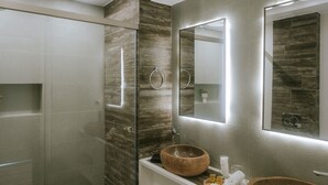 Une salle de bain moderne avec un meuble-lavabo en bois, deux vasques rondes, un grand miroir et un plafond orné de luminaires circulaires.