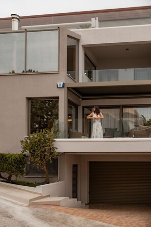 A modern two-story house with a balcony, large windows, and a garage.