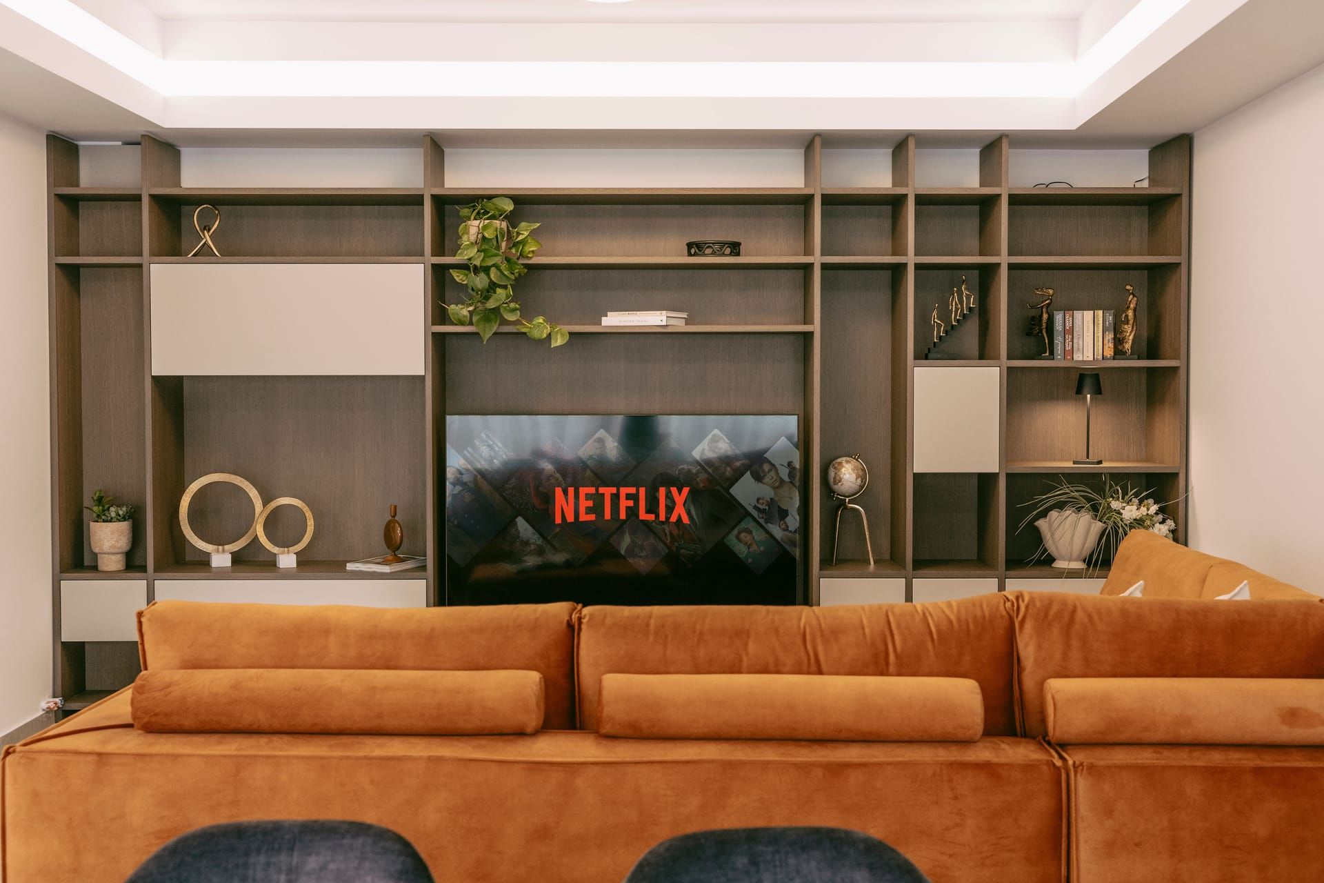 Una sala de estar con un televisor de pantalla plana grande, un sofá y estanterías empotradas con objetos decorativos.