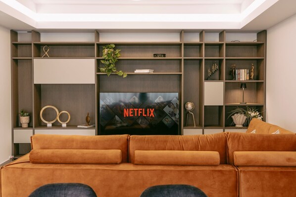 A living room with a large flat-screen TV, a sofa, and built-in shelving with decorative items.