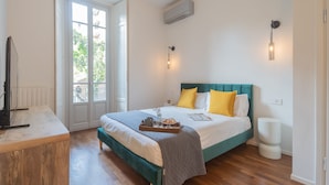 A bedroom with a bed, bedside table, and a window with a view. - Como Liberty Suites - Gatsby (Como)