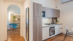 A modern kitchen with wooden cabinets, a built-in oven, and a sink. - Como Liberty Suites - Gatsby (Como)