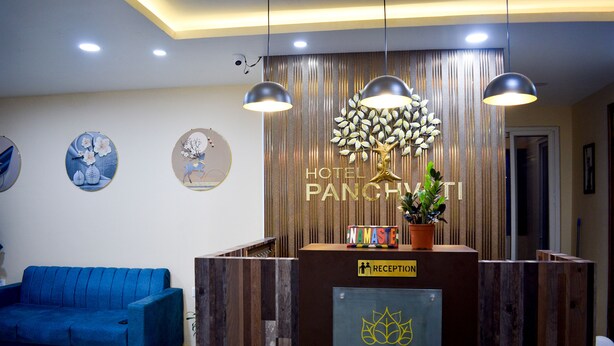 A reception desk with a sign for Hotel Panchwati, a blue sofa, and wall art. - Hotel Panchvati (Malangawa)
