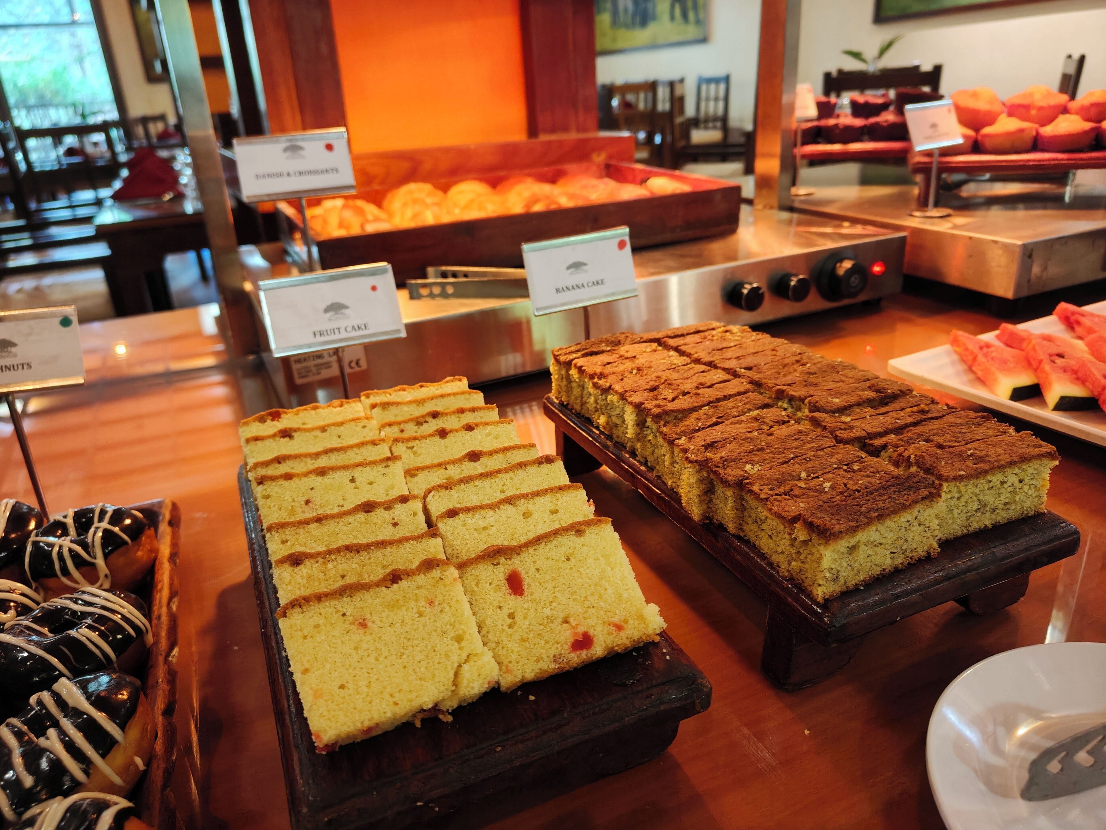 A buffet with various desserts including fruit cake, banana cake, and other baked goods.