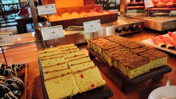 A buffet with various desserts including fruit cake, banana cake, and other baked goods.