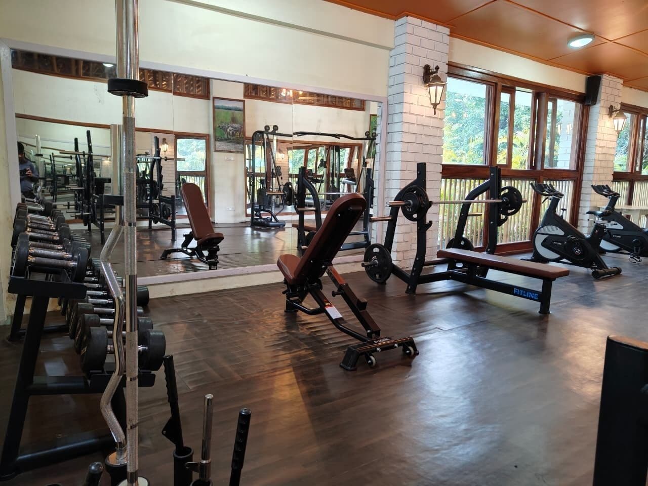 Une salle de sport équipée de divers appareils d’exercice, notamment des haltères, des bancs et des appareils de cardio.