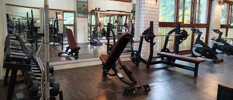 A gym with various exercise equipment, including dumbbells, benches, and cardio machines.