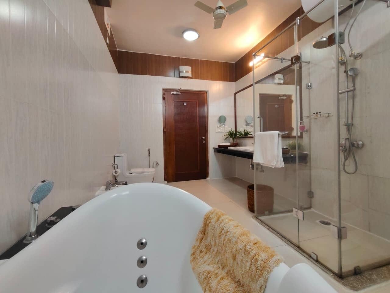 Ein modernes Badezimmer mit einer freistehenden Badewanne, einer Duschkabine und einer Holztür.