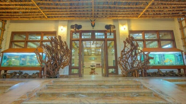 A reception area with a bamboo ceiling, large windows, and two fish tanks with aquatic displays. - Resort Borgos (Bokakhat)