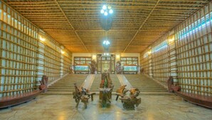 A spacious interior with a high ceiling, wooden paneling, and a central staircase leading to a balcony. - Resort Borgos (Bokakhat)