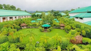 A resort with multiple buildings, a central courtyard, and lush greenery. - Resort Borgos (Bokakhat)