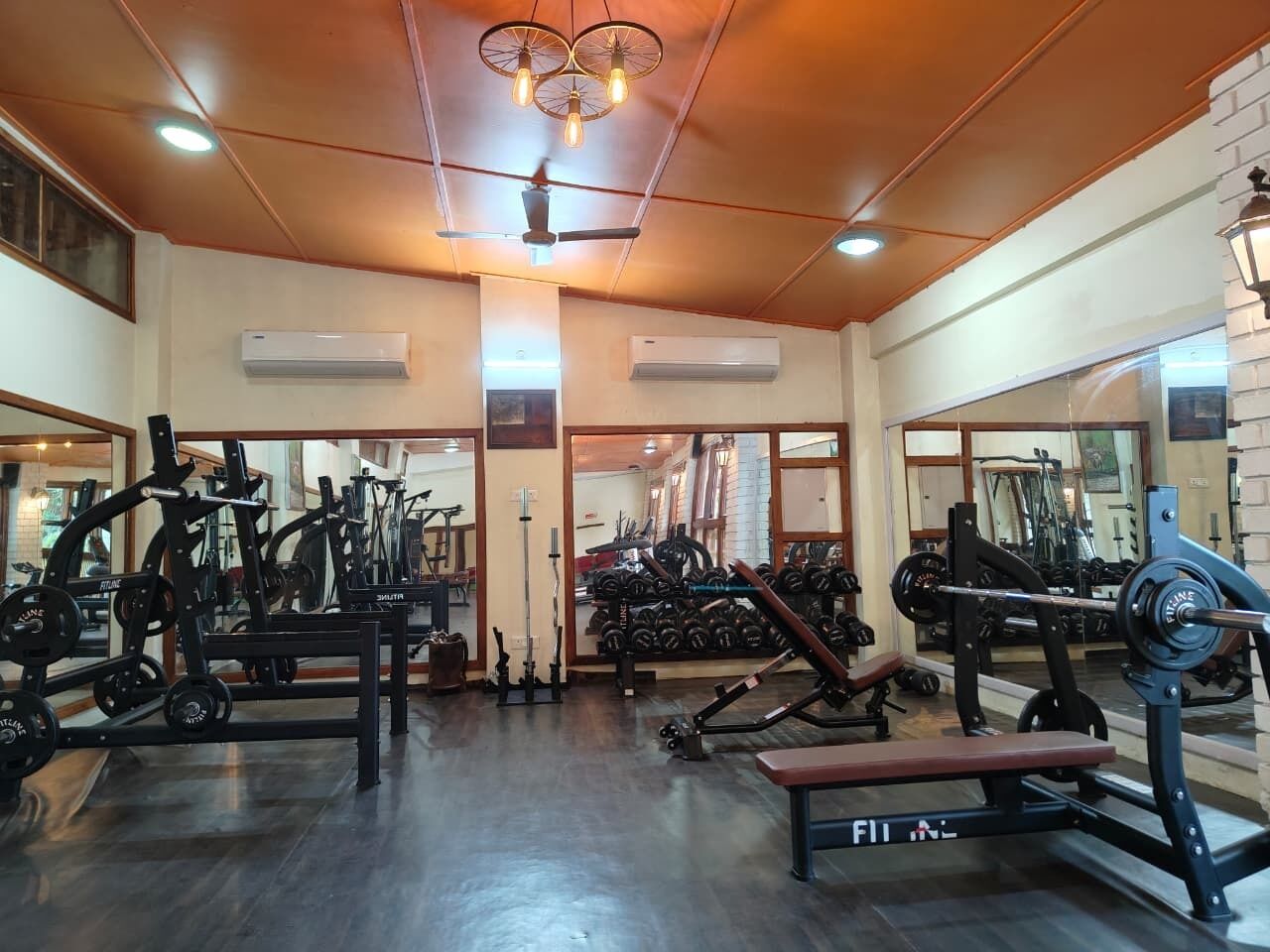 A gym with various exercise equipment, including weight machines and free weights, and a bench.