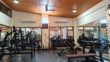 A gym with various exercise equipment, including weight machines and free weights, and a bench.