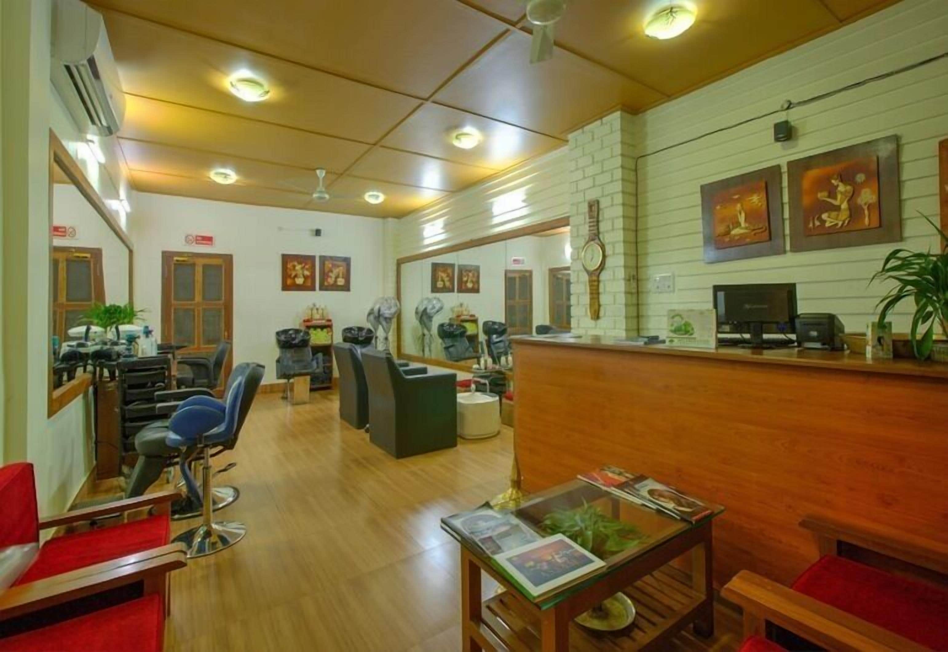 A salon with multiple hairdressing stations, a reception desk, and a few chairs.