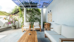 Un patio con mobiliario de madera, un sofá blanco y una mesa de centro de madera.