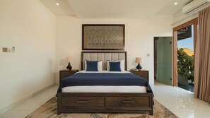 A bedroom with a bed, two bedside tables, a nightstand, a large artwork above the bed, and a view of the outdoors through a sliding door. - Villa Latima by Villa Finder (Seminyak)