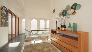 A modern interior with a staircase, a wooden console table with decorative items, and a patterned rug.