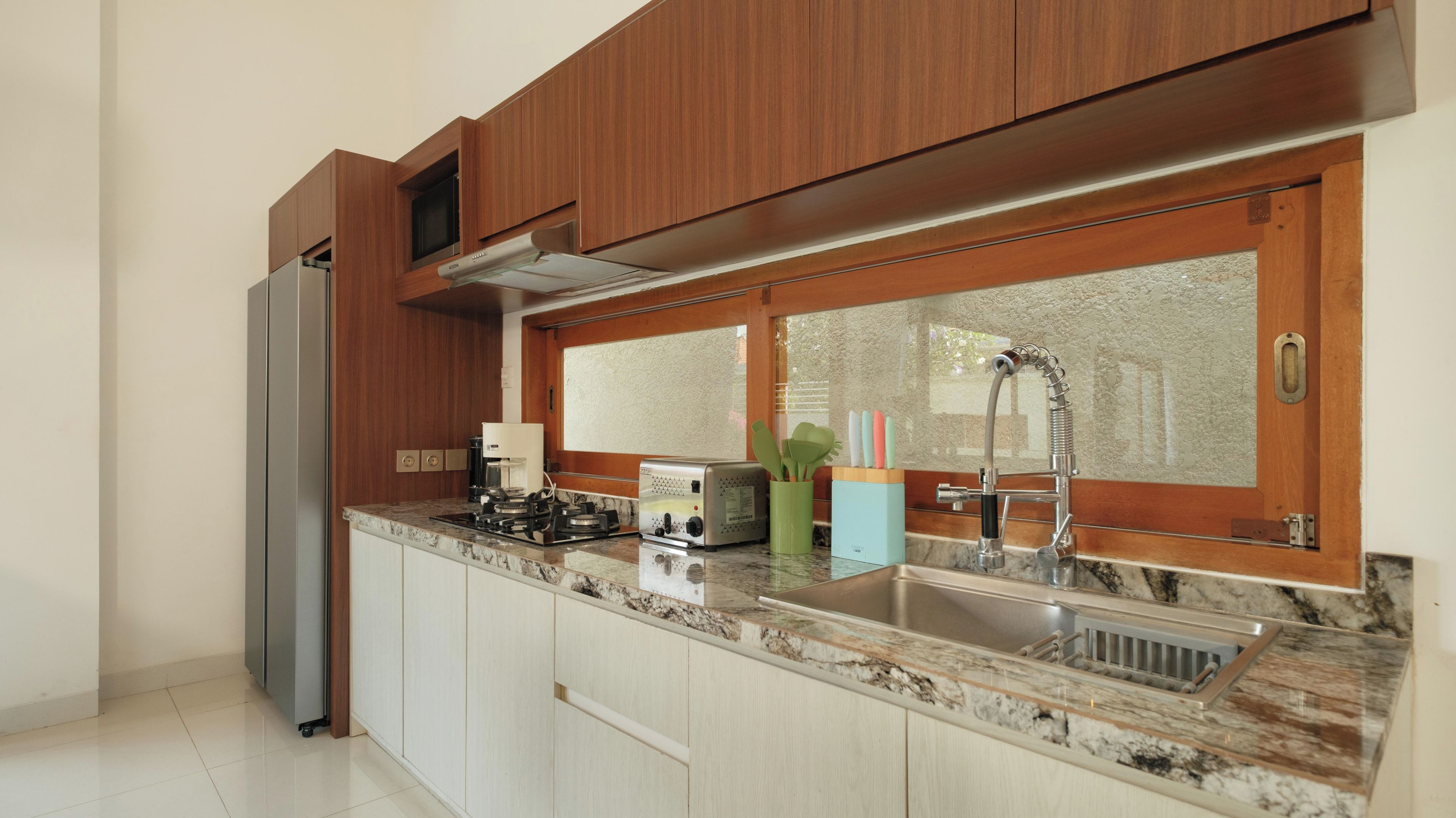 Una cocina moderna con armarios de madera, un lavamanos de acero inoxidable y una estufa empotrada.