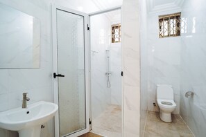 Bathroom features a glass-enclosed shower, sink, and toilet.