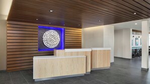 Un espace d’accueil avec des murs recouverts de lambris en bois, une œuvre d’art murale circulaire illuminée de lumière bleue et un comptoir d’accueil.