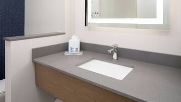 Un baño con un lavabo blanco, un espejo y un perchero para toallas.