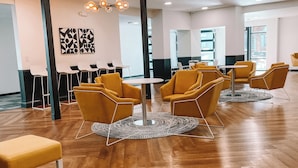 A spacious room with wooden flooring, yellow chairs, a round table, and modern ceiling lights. - Stay on M Street (Lincoln)