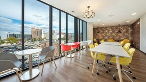 A modern conference room with large windows, a city view, and a mix of yellow and red chairs around a central table. - Stay on M Street (Lincoln)