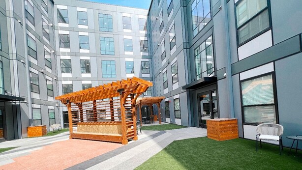 A modern outdoor area with a wooden pergola, artificial grass, and a seating area. - Stay on M Street (Lincoln)