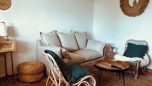 A cozy living room with a sofa, two chairs, a small table, and a lamp. There are woven baskets on the floor and a woven wall hanging. - Bungalow Avec Solarium à 5mn des Plages (Gran Alacant)