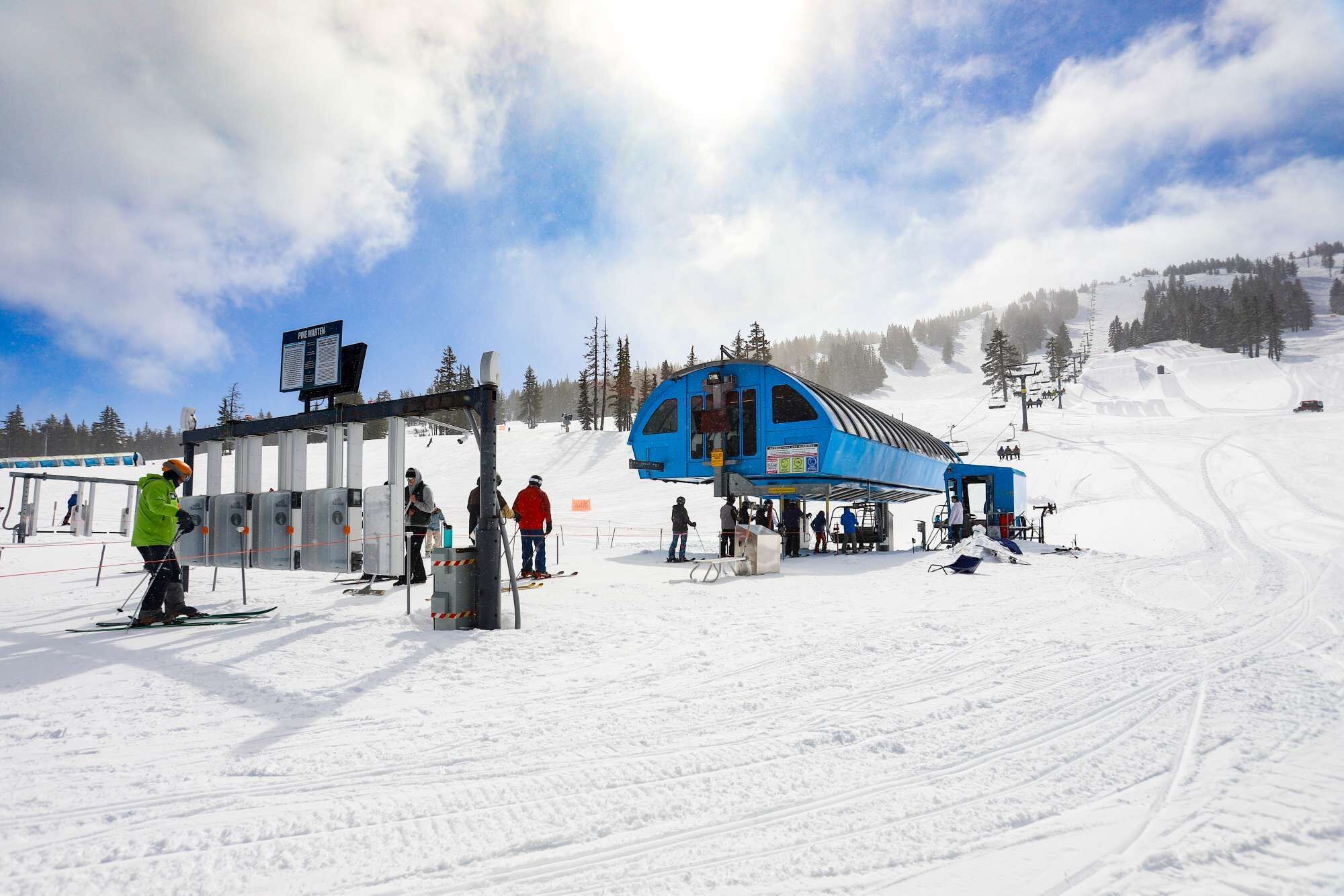 A ski lift station with a blue shelter, snow-covered ground, and a clear sky.