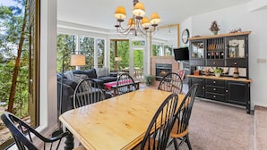 A spacious living area with a wooden dining table, black chairs, a sofa, and a fireplace. - Frosty Summit Condo at Mount Bachelor Village (Bend)