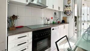 Una cocina moderna con armarios blancos, un horno negro y una mesa de comedor de vidrio.