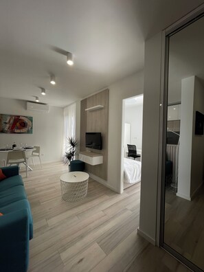 A modern living room with a flat-screen TV, a dining area with a table and chairs, and a bedroom with a bed and a nightstand. -  Point of Life 2 by Litto (Split)