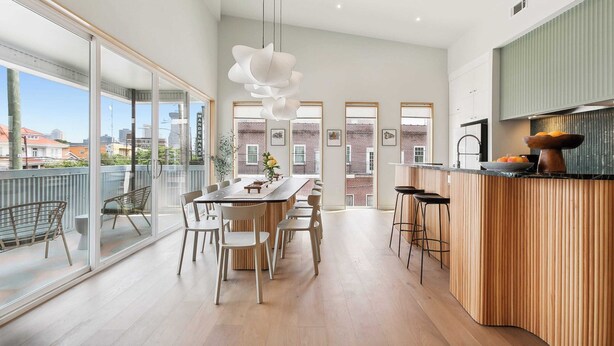 A modern kitchen with a wooden island, large windows, and a dining area with chairs. - NOLA | Heated Pool | Private Hot Tub (New Orleans)
