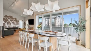 A modern kitchen with a central island, white chairs, and a large window with a view. - NOLA | Heated Pool | Private Hot Tub (New Orleans)