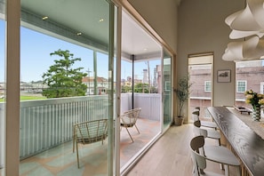 Une cuisine moderne dotée d’un grand îlot central, d’un coin repas avec des chaises et offrant une vue sur la ville grâce à de grandes fenêtres.