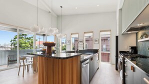 A modern kitchen with a central island, stainless steel appliances, and large windows offering views of the city. - NOLA | Heated Pool | Private Hot Tub (New Orleans)