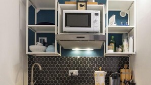 A compact kitchen with a microwave, sink, and storage cabinets. - Rione Monti Studio Apt (Rome)