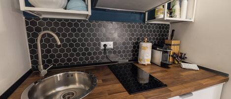 A modern kitchen with a stainless steel sink, a black hexagonal backsplash, and wooden countertops.