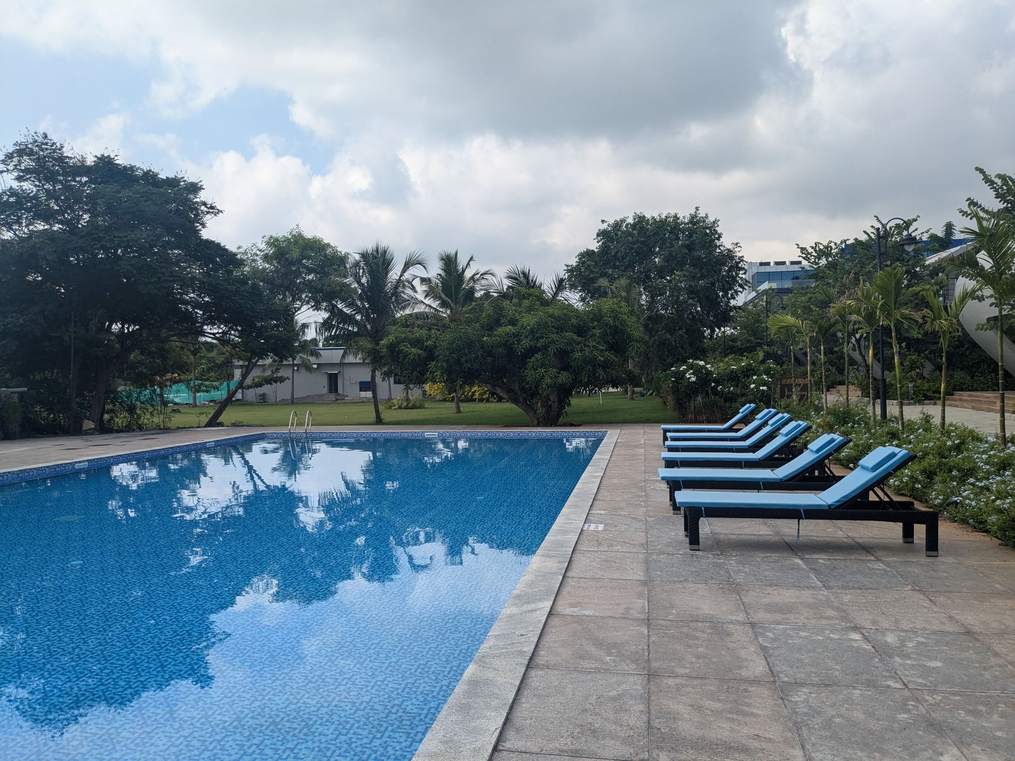 A swimming pool with blue lounge chairs and a tiled deck.