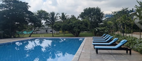A swimming pool with blue lounge chairs and a tiled deck.