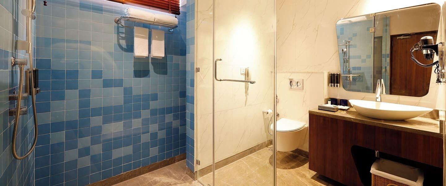A bathroom with a glass shower enclosure, a toilet, and a sink with a mirror.
